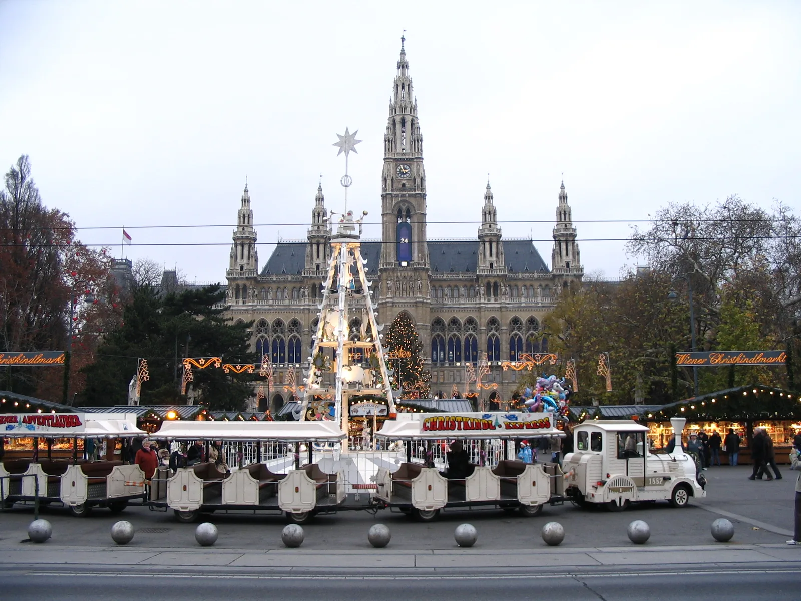 A small tourist train passing Vienna Christmas Market in front of City Hall