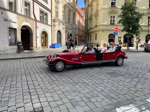 Red open-top sightseeing vehicle on a cobbled Prague street